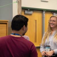 Three students smile while talking about a poster presentation